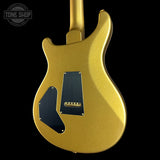 The back of a gold metallic electric guitar with black pickguards and a gold humbucker pickup, shown against a solid black background with a Tone Shop watermark in the top left.