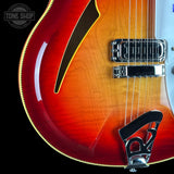 Close-up of a red electric guitar with a black pickguard on a black background.