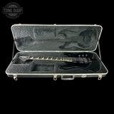 Black electric guitar in an open hardshell case with 'Tone Shop' logo.