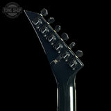Close-up of a guitar headstock with tuning pegs on a black background, featuring the Tone Shop logo.