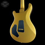 The back of a gold metallic electric guitar with dark blue pickguards, shown against a solid black background with a Tone Shop watermark in the top left corner.