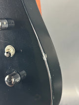 Close-up of a guitar with a visible brand logo on a plain background