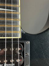 Close-up of a black electric guitar with visible strings and body details.