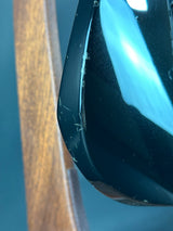 Close-up of a car's side mirror with water droplets on a wooden surface.