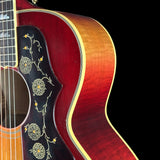 Close-up of a red acoustic guitar with decorative inlay on a black background