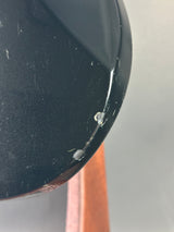 Close-up of a dark object with water droplets on a gray background