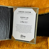 A Gibson Custom Certificate of Authenticity insert for a Murphy Lab heavy-aging instrument, shown inside an open Gibson case on a textured orange surface.