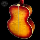 Close-up of a guitar with a sunburst finish on a black background, featuring the Tone Shop logo.