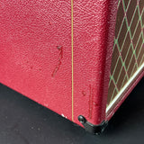 Close-up of a red guitar amplifier with visible wear on a black surface