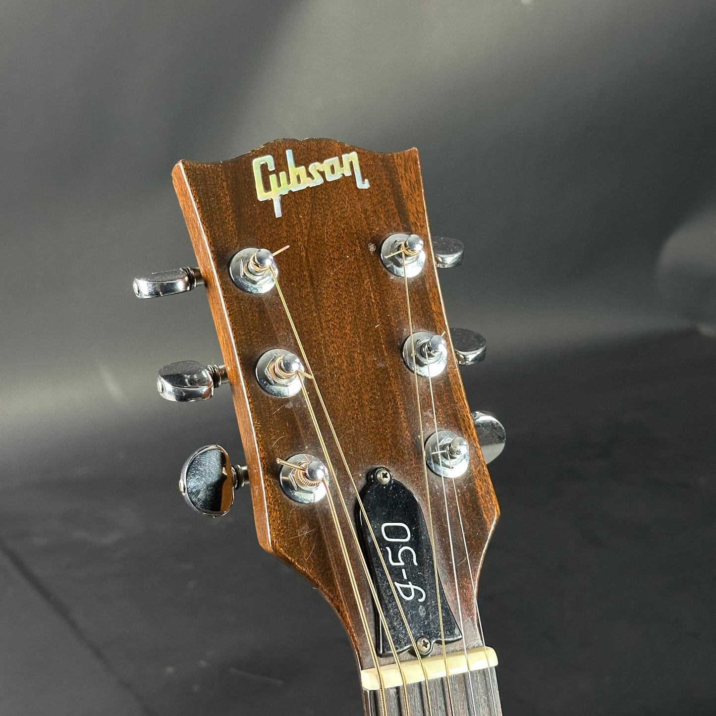 Gibson guitar headstock with tuning pegs on a dark background