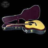 Acoustic guitar in a hard-shell case with 'Tone Shop' logo.