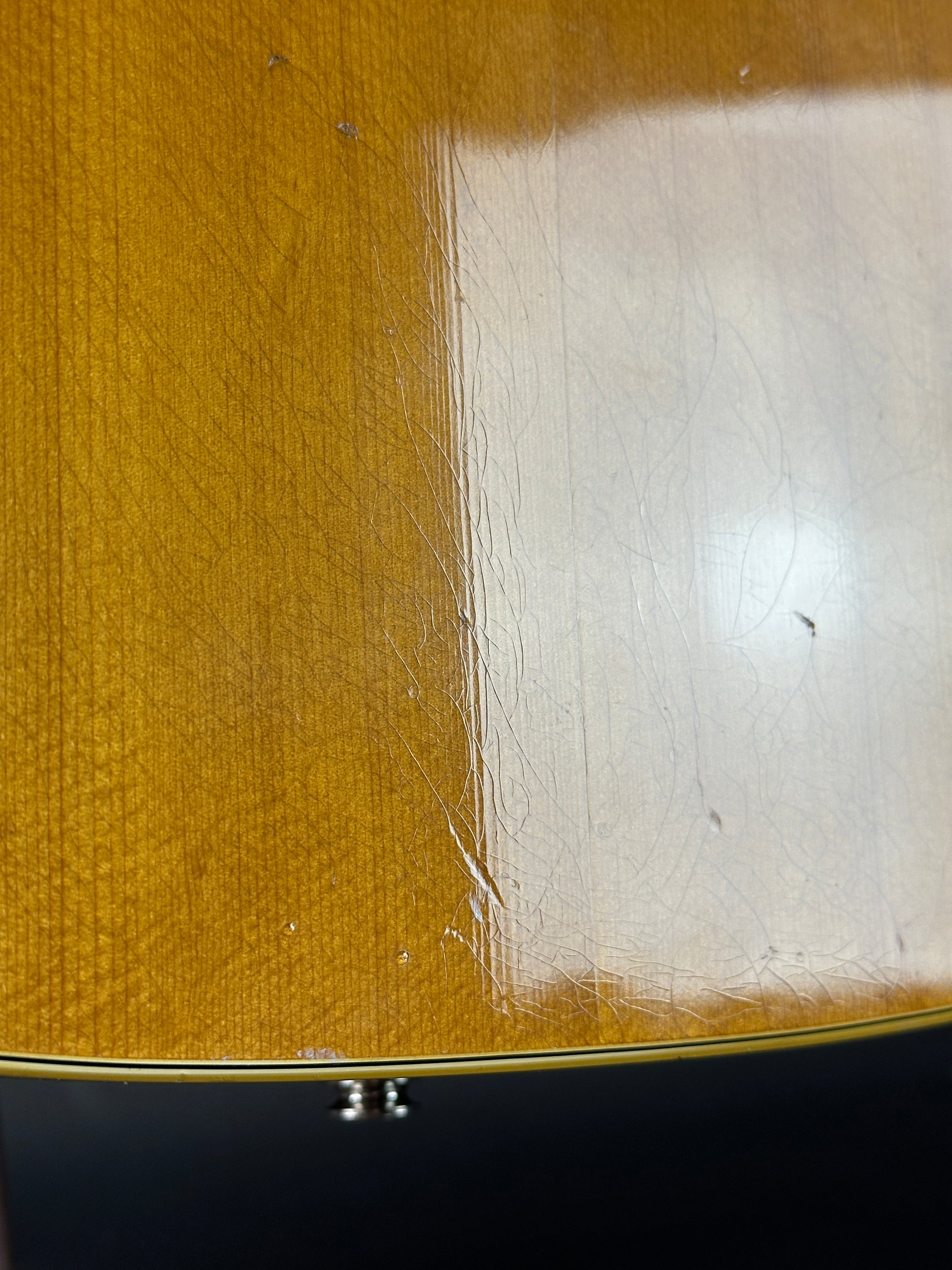 Close-up of a guitar's body with a white patch and visible wood grain.