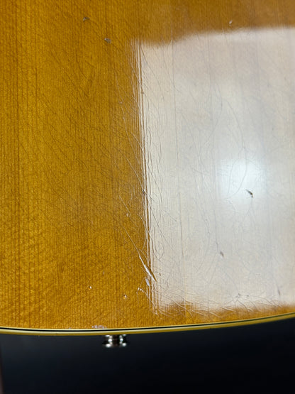 Close-up of a guitar's body with a white patch and visible wood grain.