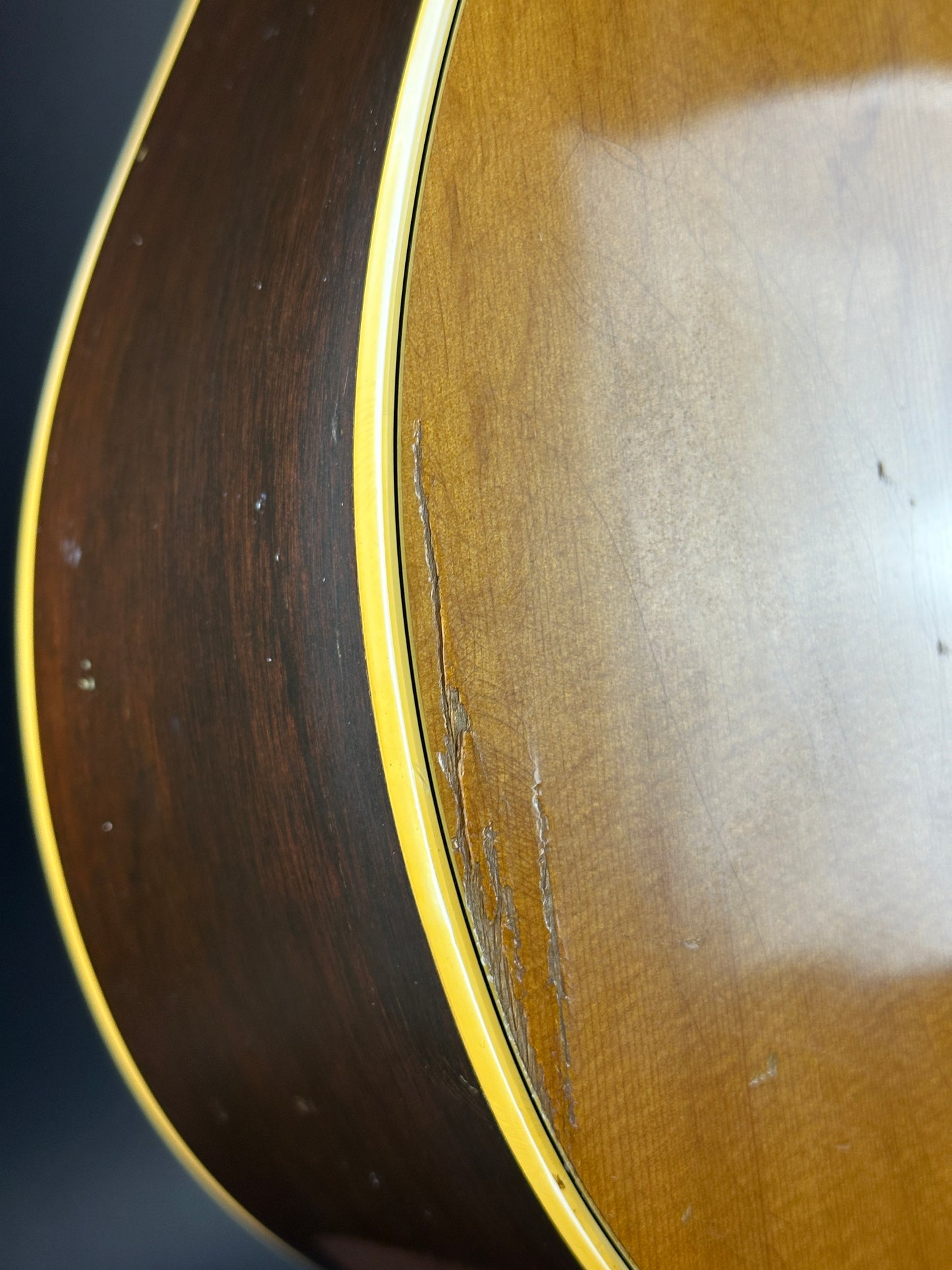 Close-up of a guitar's wooden body with a visible crack.