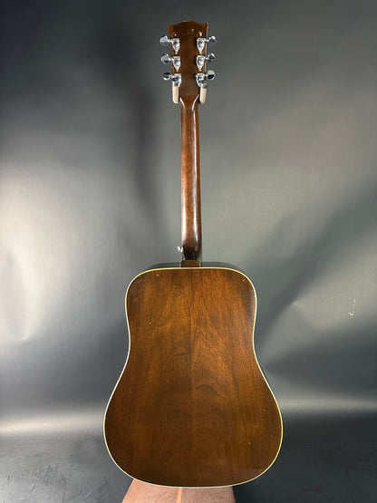 Brown acoustic guitar on a reflective gray surface