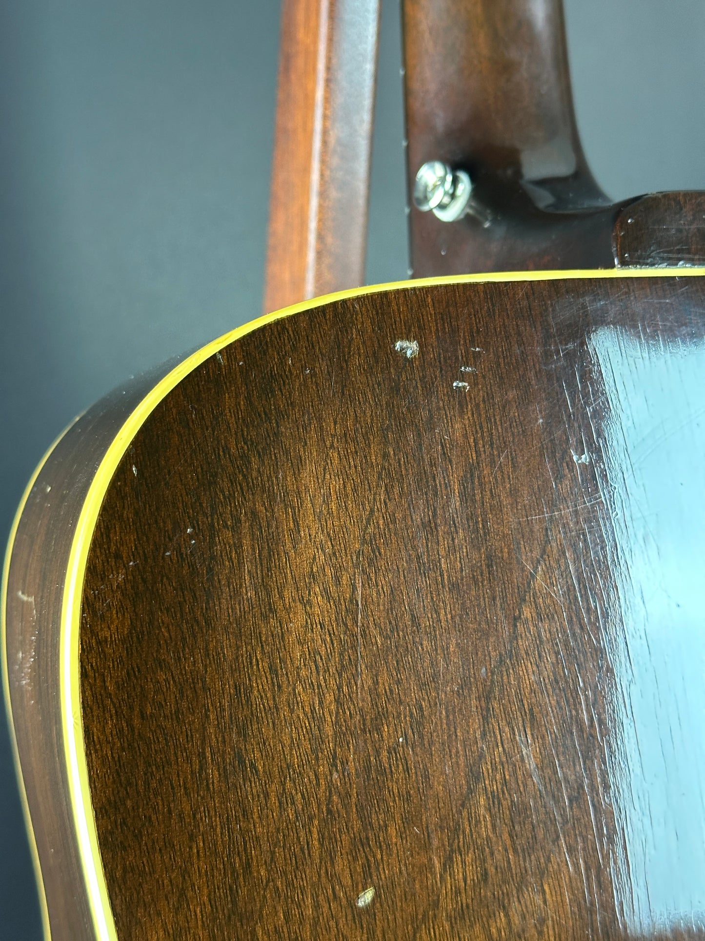 Close-up of a guitar's wooden body with a dark finish.