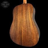 Close-up of a wooden acoustic guitar back with 'Tone Shop' logo.