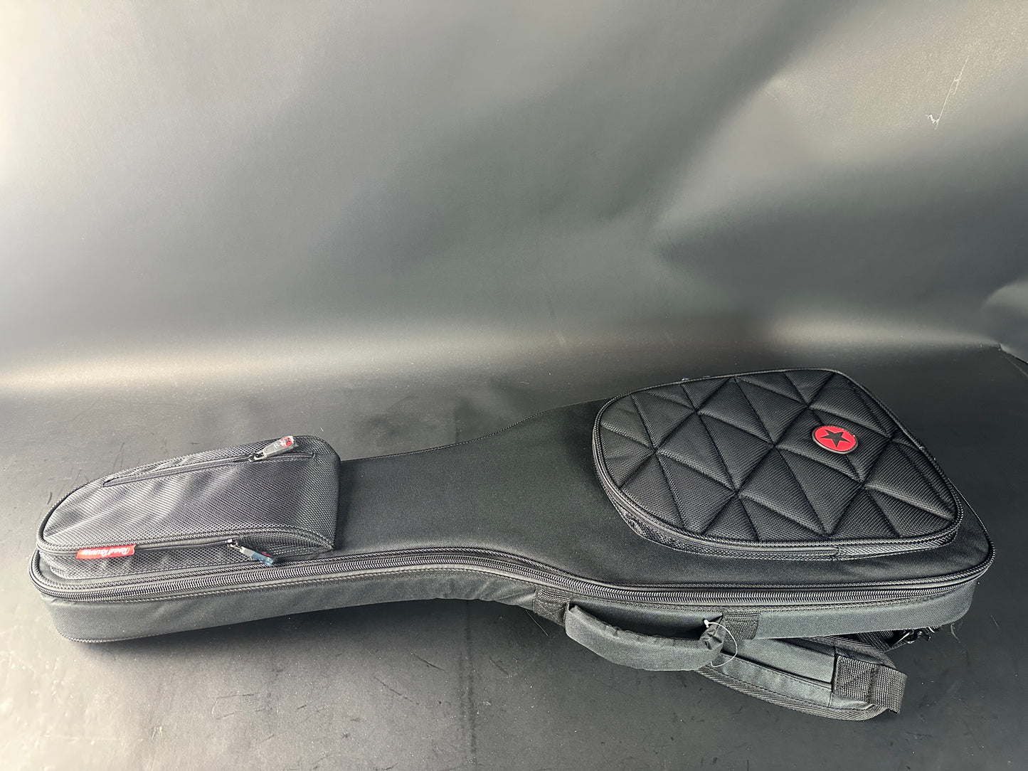Black guitar case with quilted design on a gray surface
