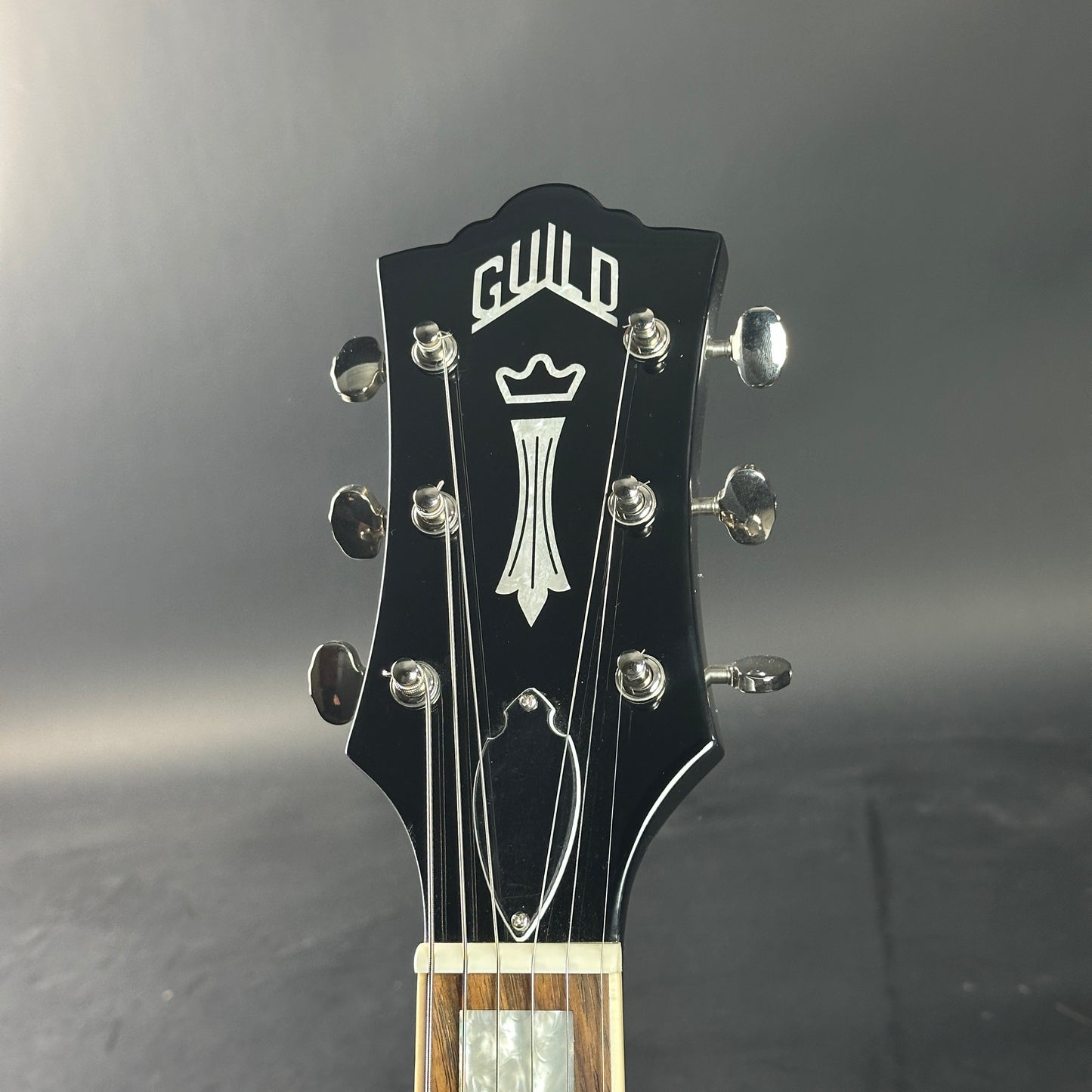 Guitar headstock withGuild logo on a gray background