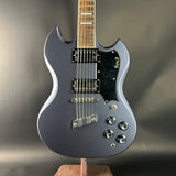 Gray electric guitar on a stand against a gray background