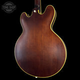 Back view of a brown electric guitar with a visible brand logo in the corner.