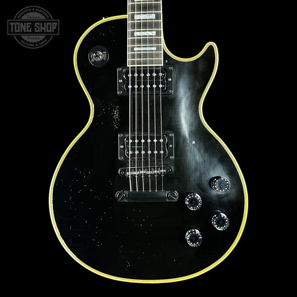 Black electric guitar with a glossy finish on a black background, featuring the 'Tone Shop' logo.