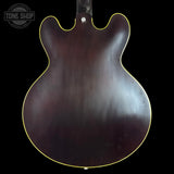 Back view of a guitar with a dark finish on a black background, featuring the Tone Shop logo.