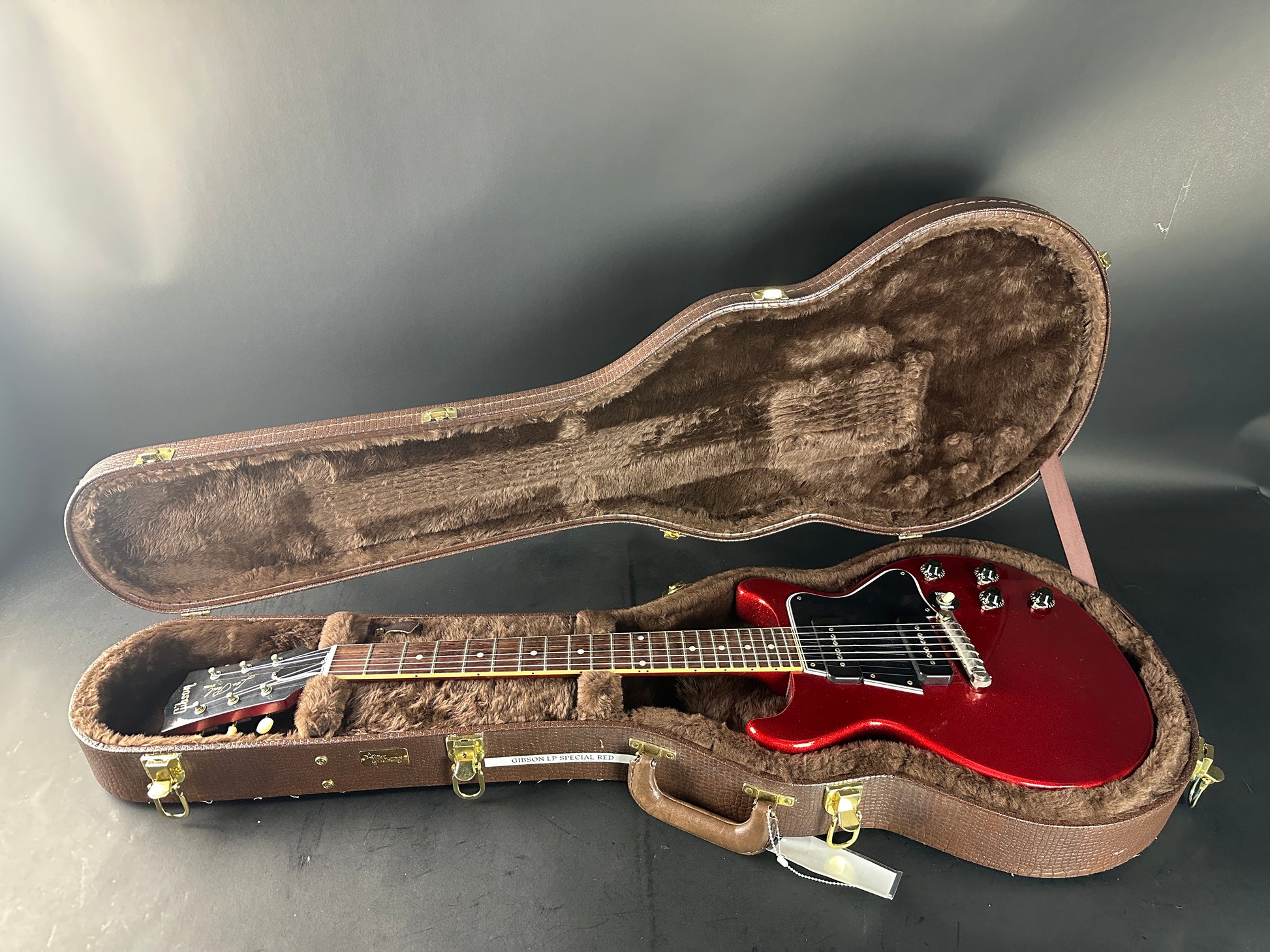 Red electric guitar in a brown case on a dark surface
