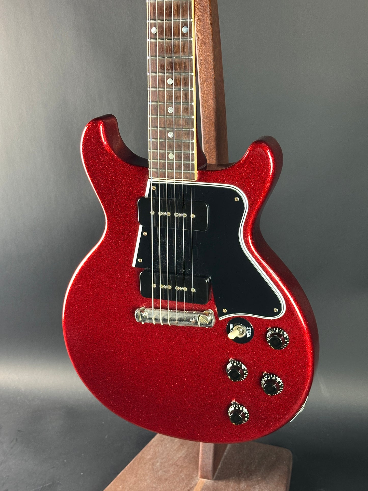 Red electric guitar on a reflective surface with a neutral background