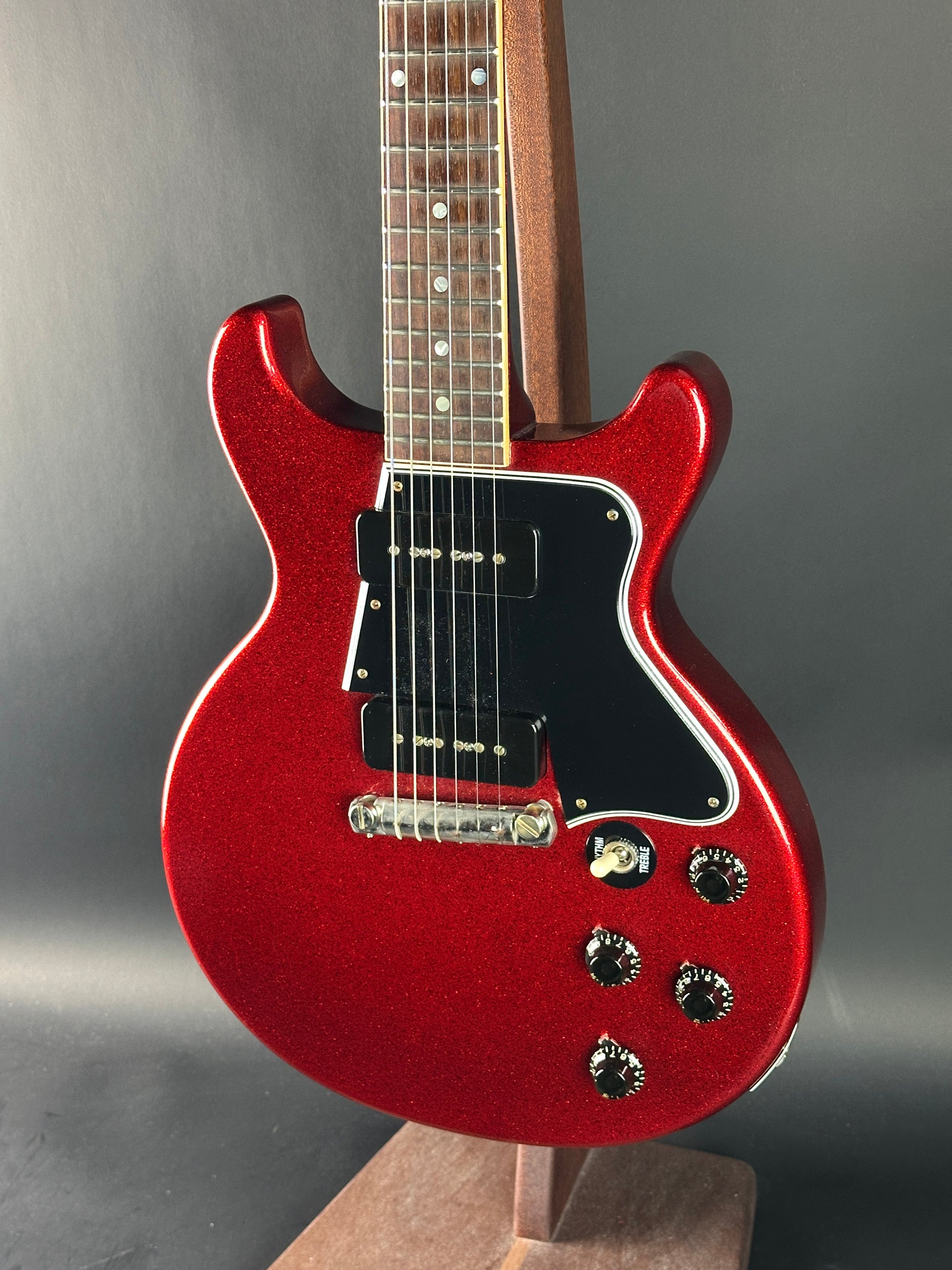Red electric guitar on a reflective surface with a neutral background