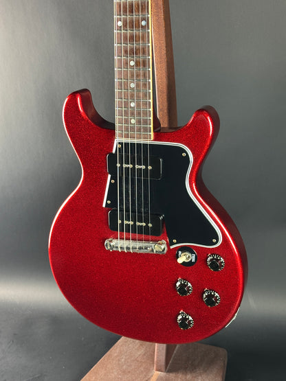 Red electric guitar on a reflective surface with a neutral background