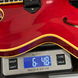 Red electric guitar on a digital scale displaying weight