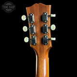 Close-up of a guitar headstock with tuning pegs on a black background, featuring the Tone Shop logo.