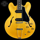 Yellow electric guitar with a black pickguard on a black background, featuring 'Tone Shop' logo.
