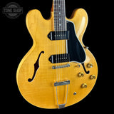 Yellow electric guitar with a black pickguard on a black background, featuring 'Tone Shop' logo.