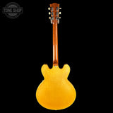 Back view of a yellow electric guitar on a black background with 'Tone Shop' logo.