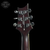 Close-up rear view of an electric guitar headstock in dark reddish-brown wood with six silver tuning pegs, shown against a black background. A Tone Shop watermark is visible in the top-left corner.