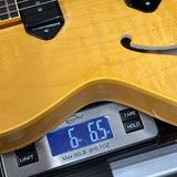 Digital scale displaying weight of a guitar, with a close-up view of the scale and guitar.