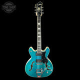 Blue electric guitar on a black background with 'Tone Shop' logo.
