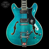 Turquoise electric guitar with a black pickguard on a black background, featuring 'Tone Shop' branding.