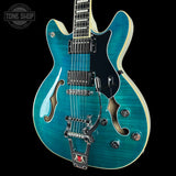 Blue electric guitar with a black pickguard on a black background, featuring 'Tone Shop' branding.