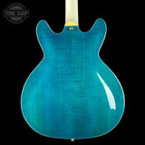 Blue electric guitar body on a black background with 'Tone Shop' logo.