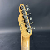 Close-up of a guitar headstock with tuning pegs on a dark background