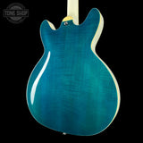 Teal electric guitar body with a visible brand logo in the corner.