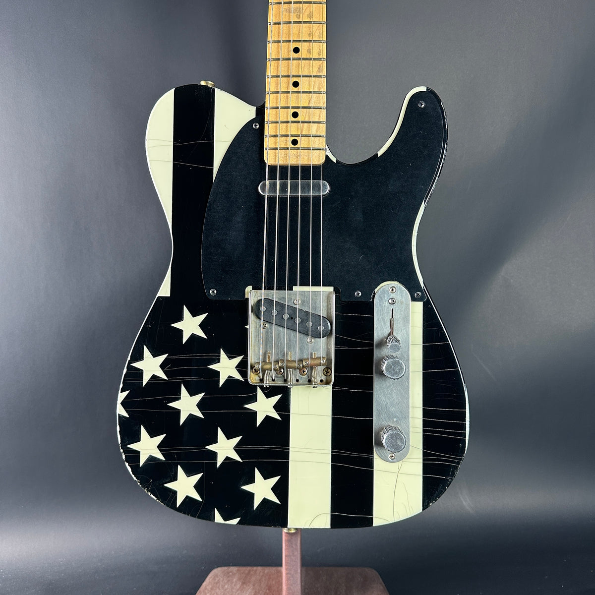 Black electric guitar with white star pattern on a dark gray background