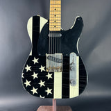 Black electric guitar with white star pattern on a dark gray background