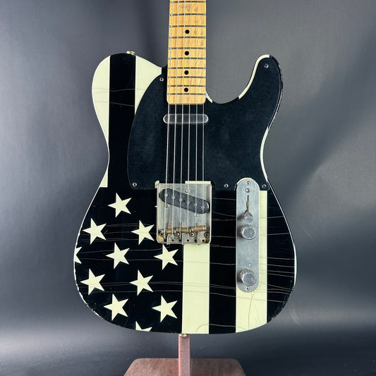 Black electric guitar with white star pattern on a dark gray background