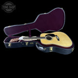 Acoustic guitar in an open case with 'Tone Shop' branding.
