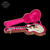 White electric guitar in a pink interior guitar case on a black background with 'Tone Shop' logo.