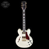 White electric guitar with a red pickguard on a black background, featuring the Tone Shop logo.